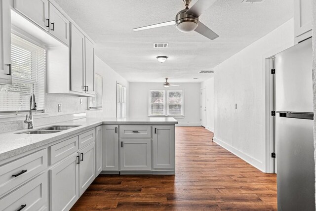 1020 S 23rd St, Temple, TX 76504 - kitchen with a ceiling fan, a peninsula, freestanding refrigerator, a textured ceiling, and dark wood-style floors