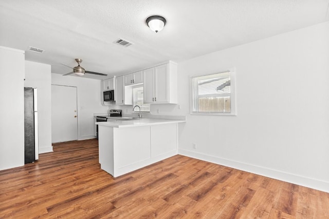 1020 S 23rd St, Temple, TX 76504 - kitchen featuring light countertops, a peninsula, wood finished floors, freestanding refrigerator, and black microwave