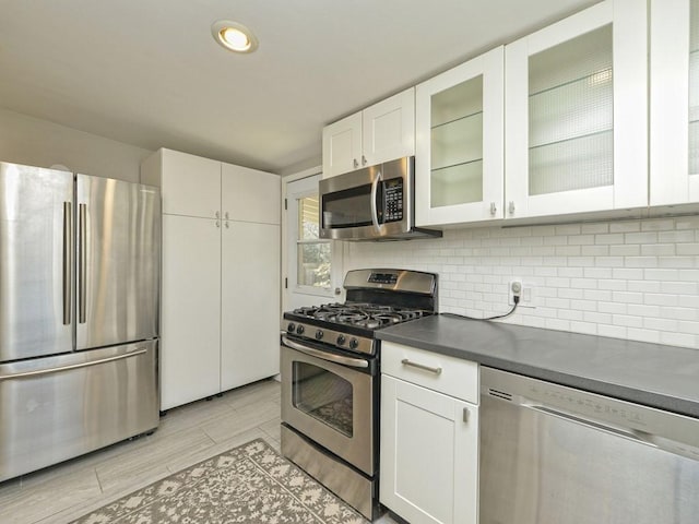 4408 Mount Vernon Dr, Austin, TX 78745 - kitchen with stainless steel appliances, dark countertops, tasteful backsplash, glass insert cabinets, and white cabinets