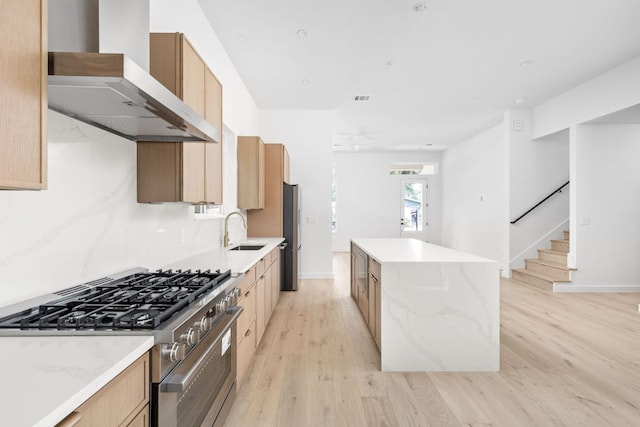 2917 Lyons Rd Unit 1, Austin, TX 78702 - kitchen featuring appliances with stainless steel finishes, a center island, light wood finished floors, wall chimney exhaust hood, and light brown cabinets