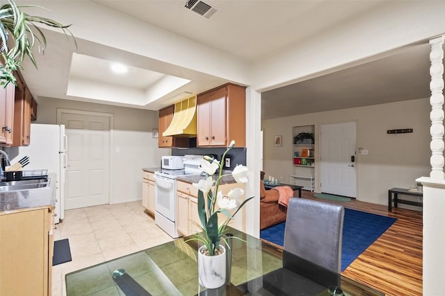 2503 Parker Ln Unit A & B, Austin, TX 78741 - kitchen with a raised ceiling, white appliances, custom exhaust hood, and light tile patterned flooring