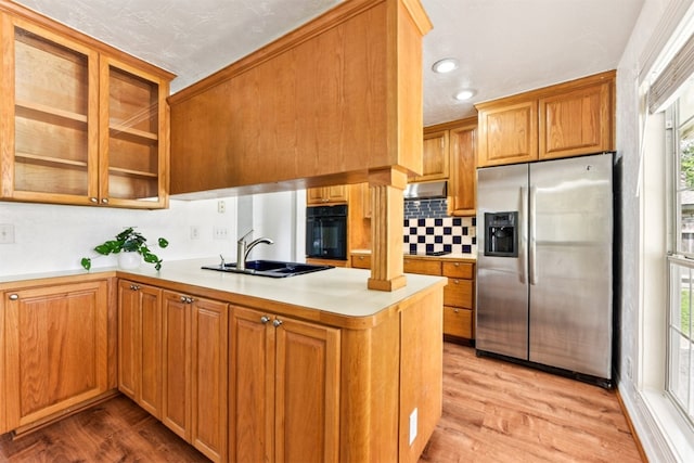 8511 Slant Oak Dr, Austin, TX 78729 - kitchen featuring stainless steel fridge with ice dispenser, a peninsula, light countertops, black oven, and backsplash