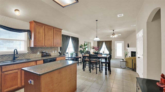 11017 Casitas Dr, Austin, TX 78717 - kitchen featuring light tile patterned floors, a kitchen island, decorative backsplash, brown cabinetry, and dark countertops