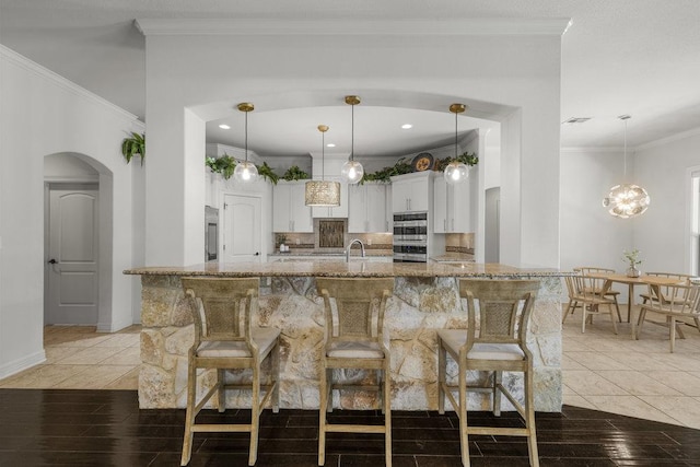 100 Eagle Landing Dr, Belton, TX 76513 - kitchen with white cabinetry, a breakfast bar area, light stone counters, decorative backsplash, and light tile patterned flooring
