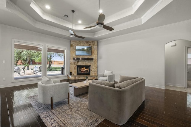 100 Eagle Landing Dr, Belton, TX 76513 - living room with arched walkways, a raised ceiling, crown molding, a stone fireplace, and dark wood finished floors