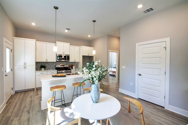 6111 Carnation Ter Unit 1, Austin, TX 78741 - kitchen featuring tasteful backsplash, stainless steel appliances, white cabinetry, light countertops, and light wood-style flooring