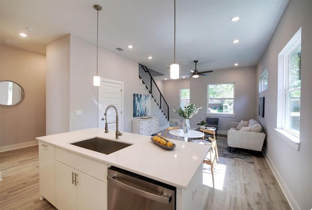 6111 Carnation Ter Unit 1, Austin, TX 78741 - kitchen with light wood-style floors, stainless steel dishwasher, a kitchen island with sink, white cabinets, and recessed lighting