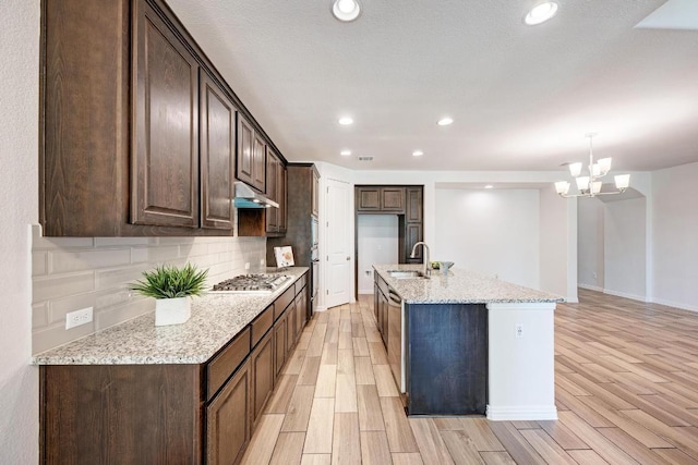 2953 Diego Dr, Round Rock, TX 78665 - kitchen featuring dark brown cabinetry, light wood finished floors, decorative backsplash, light stone countertops, and recessed lighting