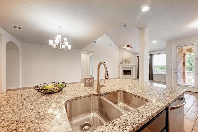 2953 Diego Dr, Round Rock, TX 78665 - kitchen with a tile fireplace, vaulted ceiling, light stone counters, open floor plan, and a chandelier