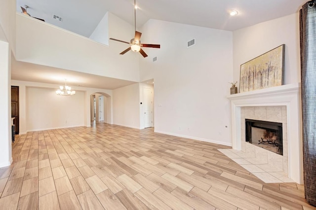 2953 Diego Dr, Round Rock, TX 78665 - unfurnished living room featuring a tiled fireplace, a ceiling fan, a chandelier, light wood-style floors, and arched walkways