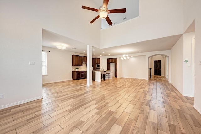 2953 Diego Dr, Round Rock, TX 78665 - unfurnished living room with a ceiling fan, light wood-type flooring, arched walkways, a chandelier, and a high ceiling