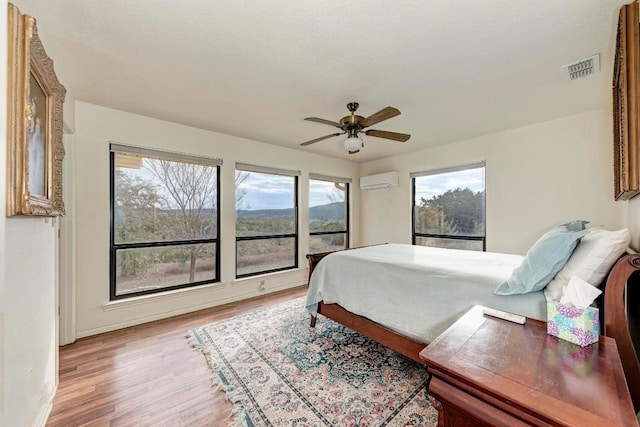 817 Mountain Creek Rd, Marble Falls, TX 78654 - bedroom with light wood finished floors, a ceiling fan, and an AC wall unit