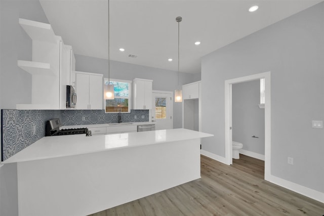 1104 Begonia Ter Unit 2, Austin, TX 78741 - kitchen featuring a peninsula, decorative backsplash, open shelves, white cabinetry, and light wood-style flooring