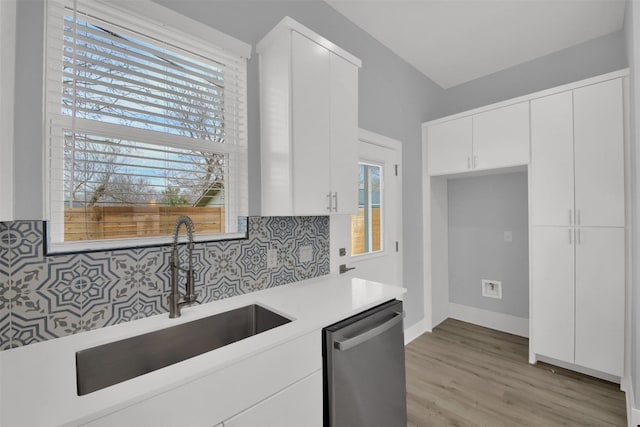 1104 Begonia Ter Unit 2, Austin, TX 78741 - kitchen with light countertops, dishwasher, backsplash, white cabinets, and light wood-style flooring