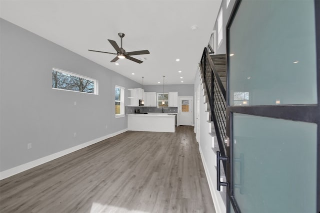 1104 Begonia Ter Unit 2, Austin, TX 78741 - unfurnished living room featuring wood finished floors, stairway, a ceiling fan, and recessed lighting