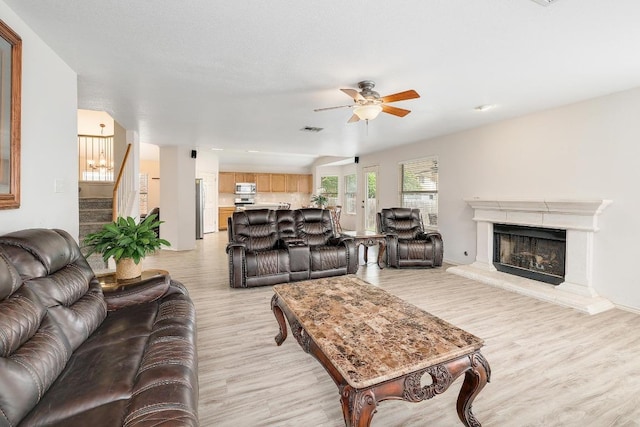 15433 Ozone Pl, Austin, TX 78728 - living room featuring light wood-style floors, ceiling fan, stairway, and a premium fireplace