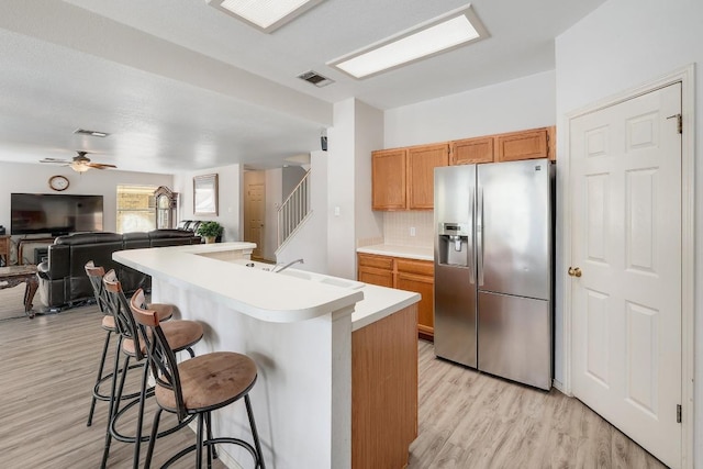 15433 Ozone Pl, Austin, TX 78728 - kitchen featuring stainless steel fridge with ice dispenser, light countertops, a breakfast bar, and light wood-style floors