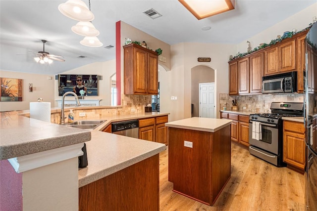 700 Stokesay Castle Path, Pflugerville, TX 78660 - kitchen with stainless steel appliances, arched walkways, a center island, light wood-type flooring, and tasteful backsplash
