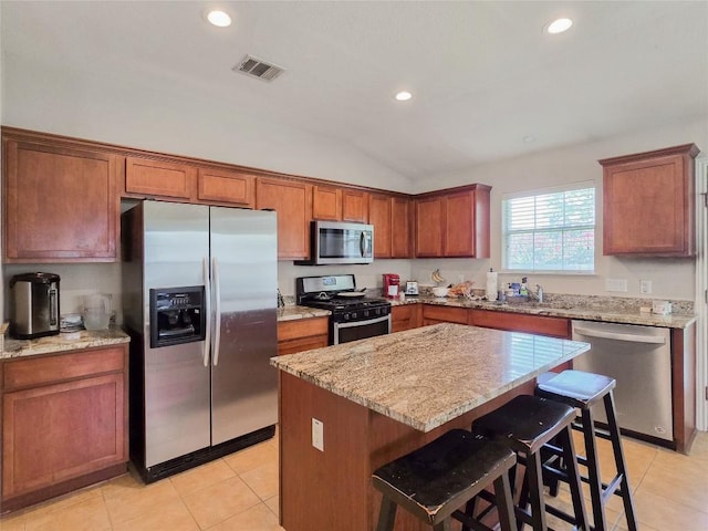 11704 Fletcher Hall Ln, Austin, TX 78717 - kitchen featuring appliances with stainless steel finishes, recessed lighting, light stone countertops, a kitchen island, and vaulted ceiling