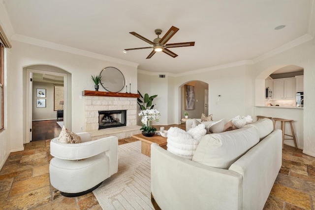 4700 River Place Blvd Unit 3, Austin, TX 78730 - living area featuring stone tile flooring, a ceiling fan, crown molding, arched walkways, and a stone fireplace