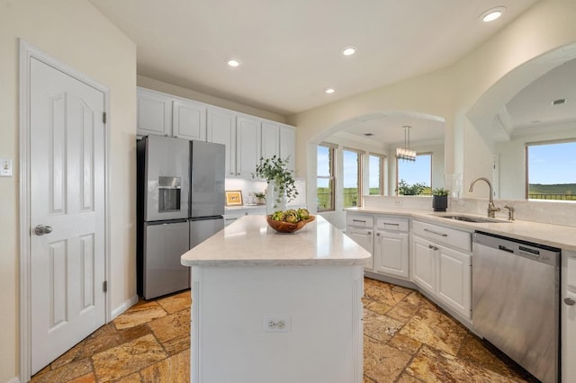 4700 River Place Blvd Unit 3, Austin, TX 78730 - kitchen with arched walkways, stone tile floors, appliances with stainless steel finishes, a kitchen island, and white cabinets