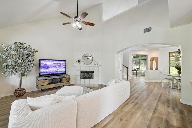 12600 Grimes Ranch Ct, Austin, TX 78732 - living area with arched walkways, wood finished floors, ceiling fan, high vaulted ceiling, and a tiled fireplace