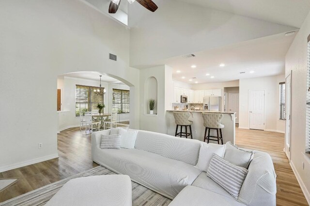 12600 Grimes Ranch Ct, Austin, TX 78732 - living area featuring arched walkways, a ceiling fan, a chandelier, light wood-style floors, and a towering ceiling