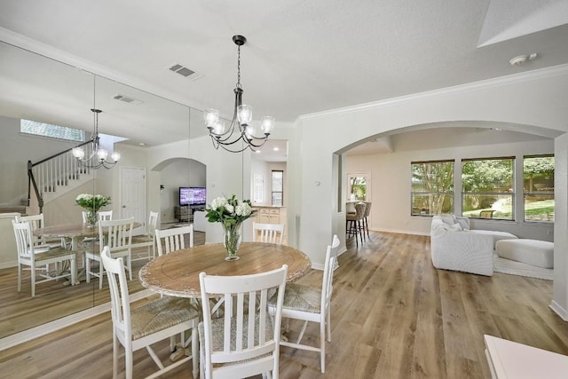 12600 Grimes Ranch Ct, Austin, TX 78732 - dining area featuring arched walkways, a chandelier, ornamental molding, and light wood-type flooring