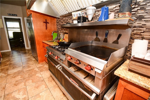 kitchen featuring light stone counters, lofted ceiling, stainless steel fridge, and sink