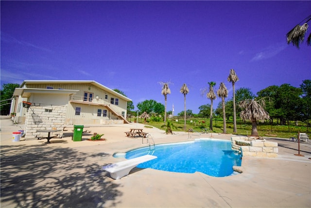 view of swimming pool featuring a patio and a diving board