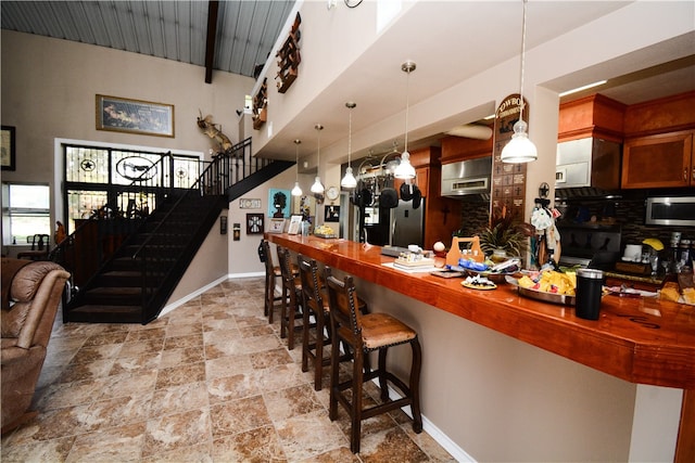 bar with hanging light fixtures, a high ceiling, and tasteful backsplash