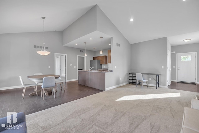 unfurnished living room with sink, high vaulted ceiling, and dark colored carpet