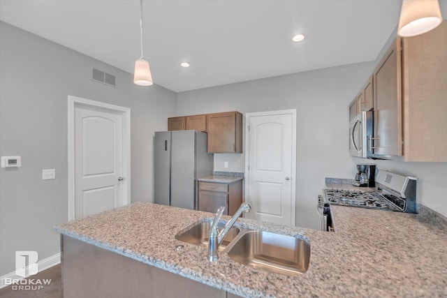 kitchen with sink, refrigerator, range with gas cooktop, light stone countertops, and decorative light fixtures