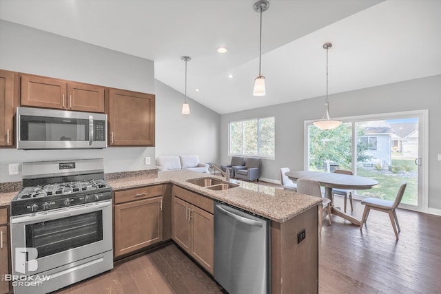 kitchen featuring stainless steel appliances, decorative light fixtures, vaulted ceiling, sink, and dark hardwood / wood-style flooring