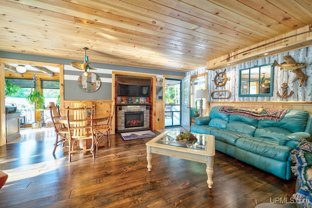 living area with wooden ceiling, a wainscoted wall, a stone fireplace, and hardwood / wood-style flooring