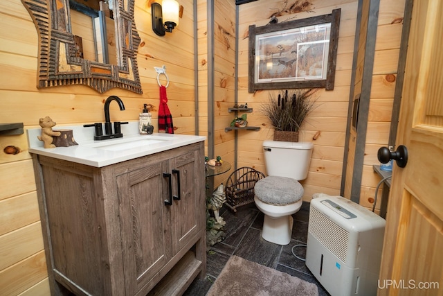 bathroom with wood walls, vanity, and toilet