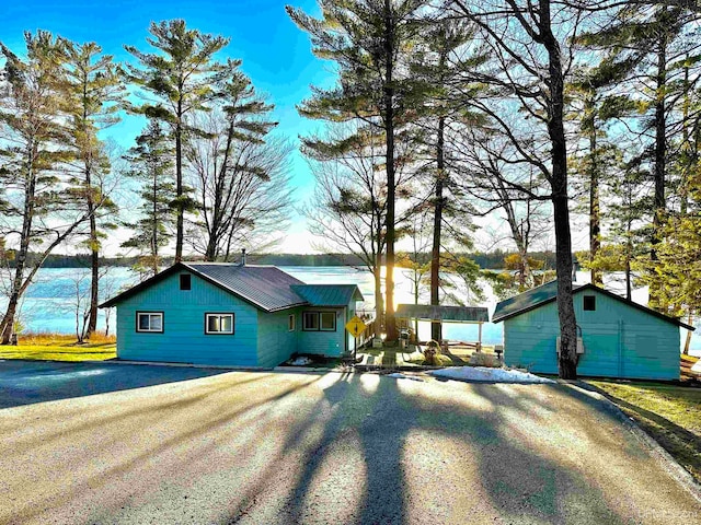 view of front facade featuring an outbuilding, metal roof, and driveway