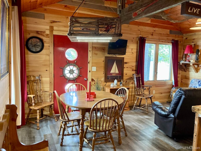 dining space with hardwood / wood-style flooring, wooden walls, and vaulted ceiling