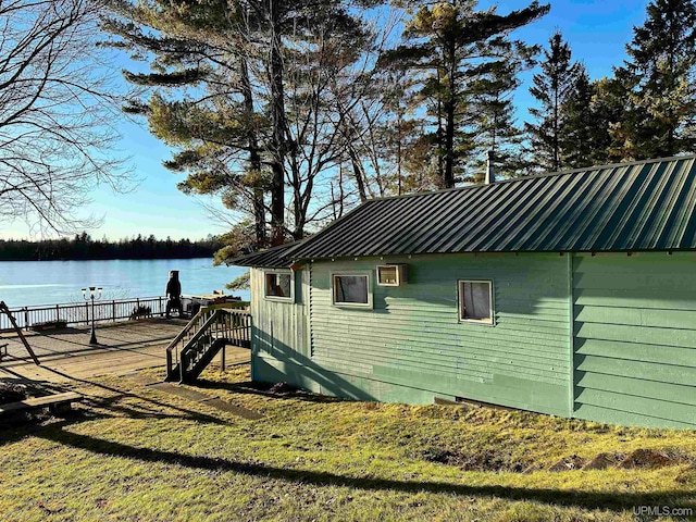 view of property exterior with crawl space, metal roof, and a deck with water view