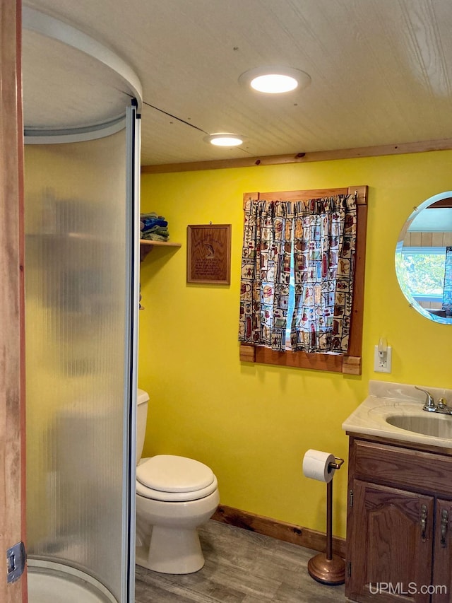 bathroom featuring a stall shower, baseboards, toilet, wood finished floors, and vanity