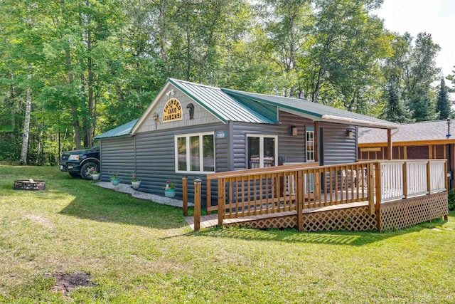 rear view of house featuring a yard, a deck, and an outdoor fire pit