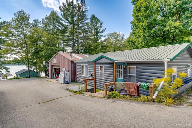 view of front of house featuring a garage, log veneer siding, metal roof, and an outdoor structure