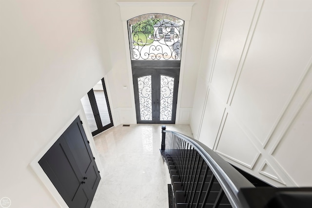 entrance foyer featuring french doors, a healthy amount of sunlight, and a high ceiling