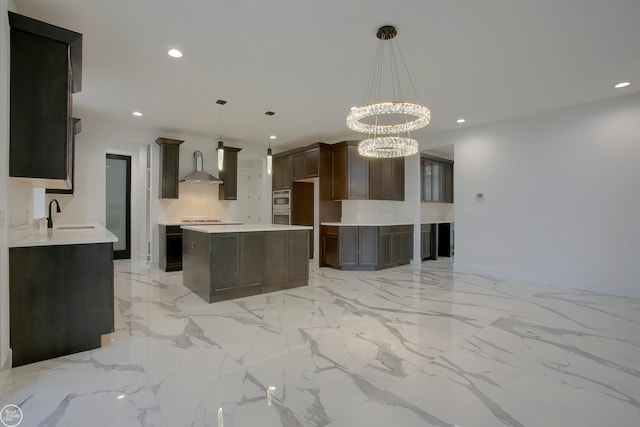 kitchen featuring a notable chandelier, light tile flooring, wall chimney range hood, a kitchen island, and decorative light fixtures