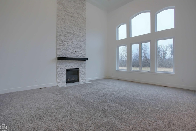 unfurnished living room with a fireplace, carpet, and a towering ceiling