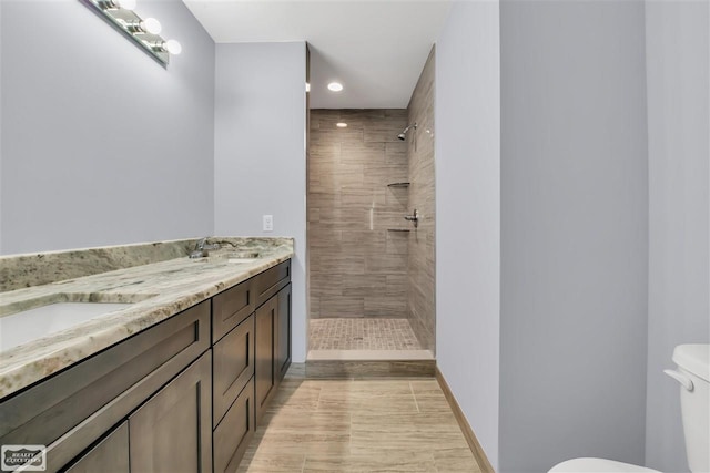 bathroom with double sink vanity, toilet, and tiled shower