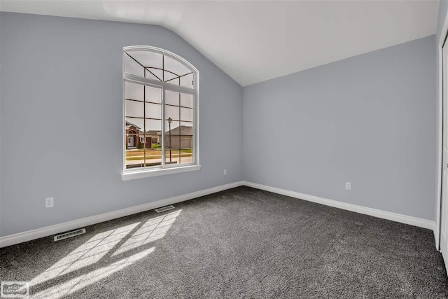 unfurnished room with lofted ceiling and dark colored carpet