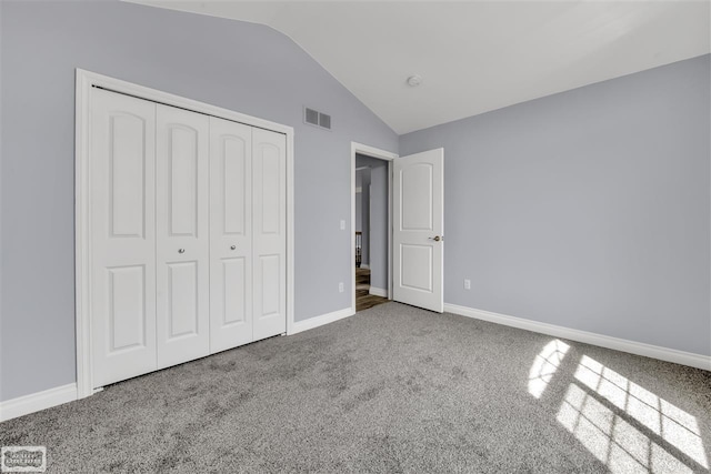 unfurnished bedroom with vaulted ceiling, dark carpet, and a closet