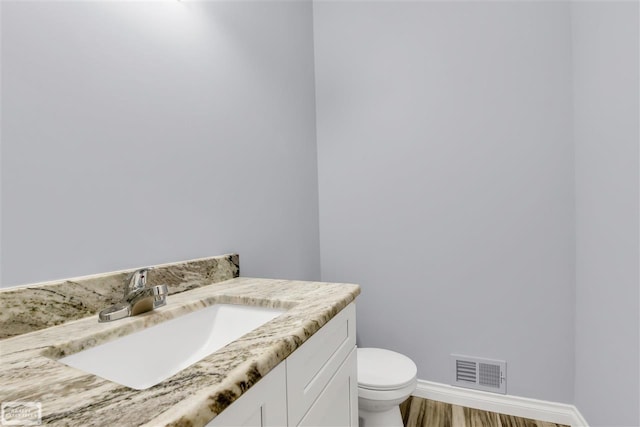 bathroom featuring toilet, vanity, and hardwood / wood-style floors