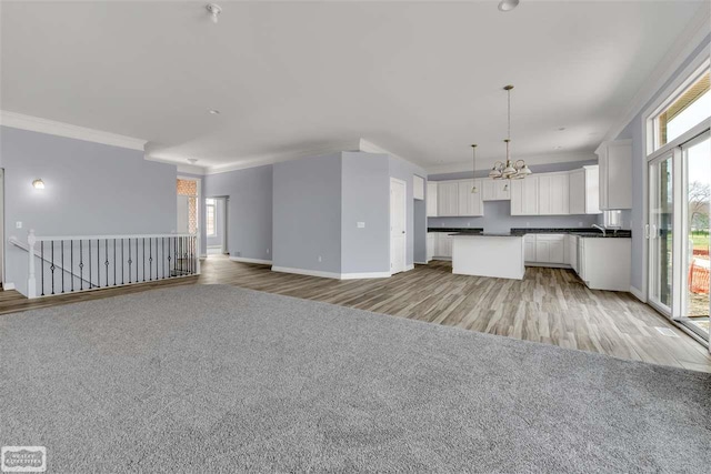 unfurnished living room with a wealth of natural light, light carpet, and a chandelier